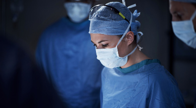 Ärztin im OP-Saal mit OP-Kittel, Mundschutz und Schutzbrille. Ärztin im OP-Saal mit OP-Kittel, Mundschutz und Schutzbrille.