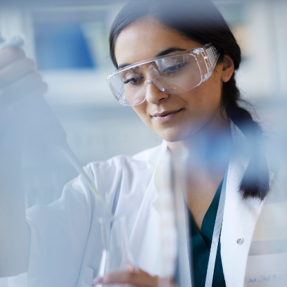 Wissenschaftlerin mit Kittel und Schutzbrille im Labor arbeitet mit einer Pipette. Wissenschaftlerin mit Kittel und Schutzbrille im Labor arbeitet mit einer Pipette.