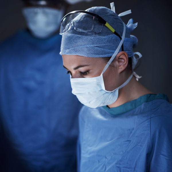 Ärztin im OP-Saal mit OP-Kittel, Mundschutz und Schutzbrille. Ärztin im OP-Saal mit OP-Kittel, Mundschutz und Schutzbrille.