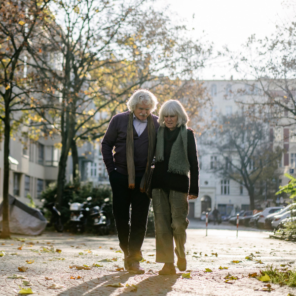 Ein älteres Paar spaziert Hand in Hand durch herbstliche Stadtstraße. Ein älteres Paar spaziert Hand in Hand durch herbstliche Stadtstraße.