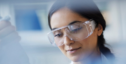 Wissenschaftlerin mit Kittel und Schutzbrille im Labor arbeitet mit einer Pipette. Wissenschaftlerin mit Kittel und Schutzbrille im Labor arbeitet mit einer Pipette.